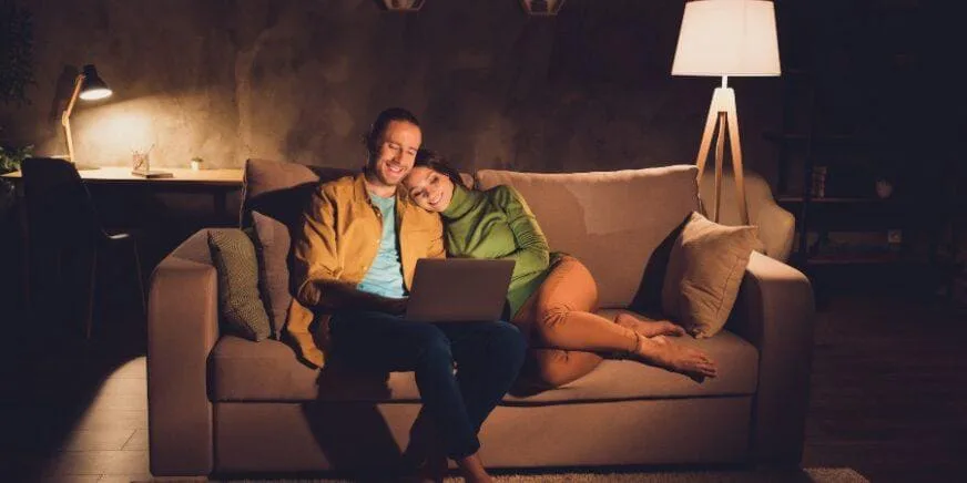 Paar sitzt gemütlich auf Sofa und sucht nach Lampen für ihr Zuhause